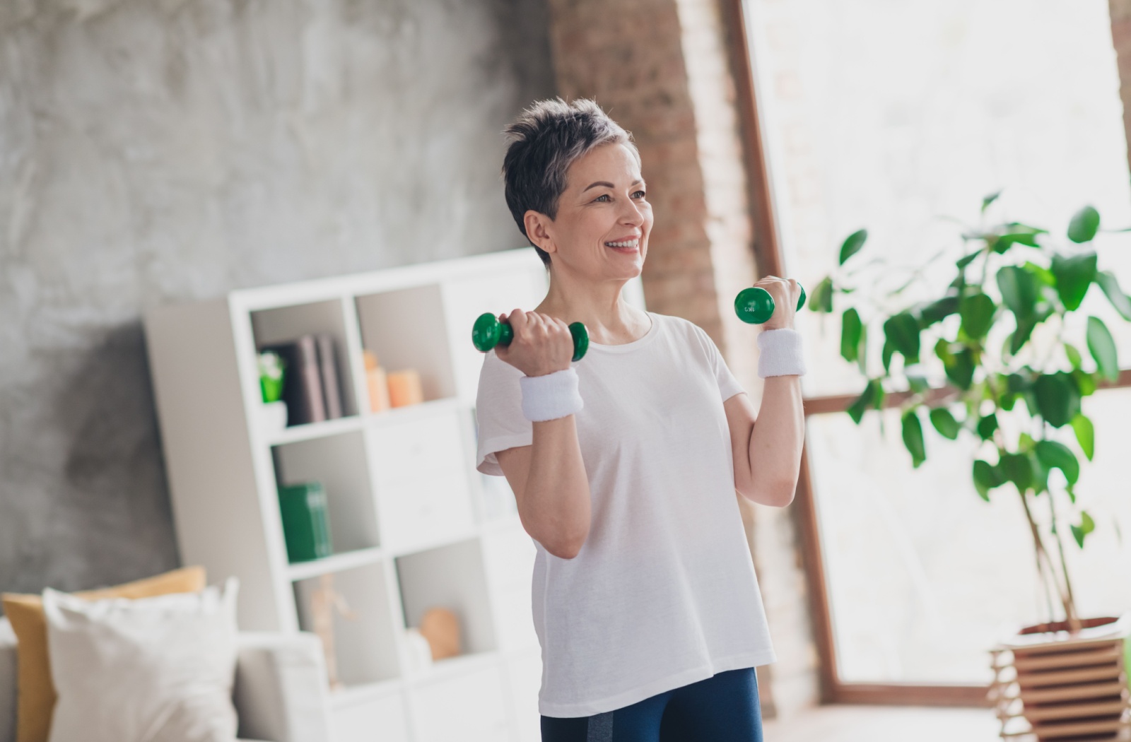 A senior exercises with free-weights to promote active movement and ease her arthritis pain.