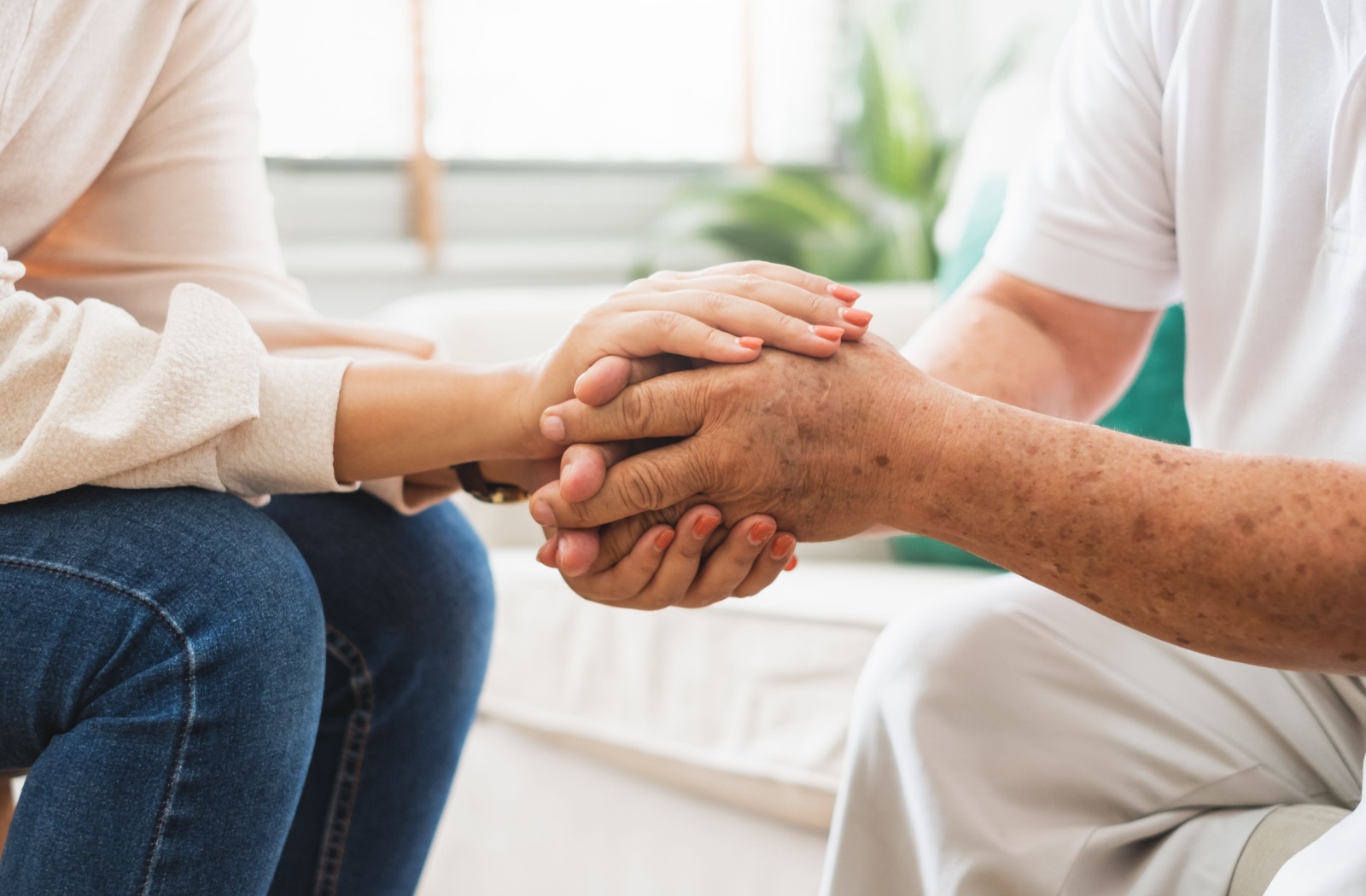 A caregiver clasping the hands of their older parent and trying to stay supportive.