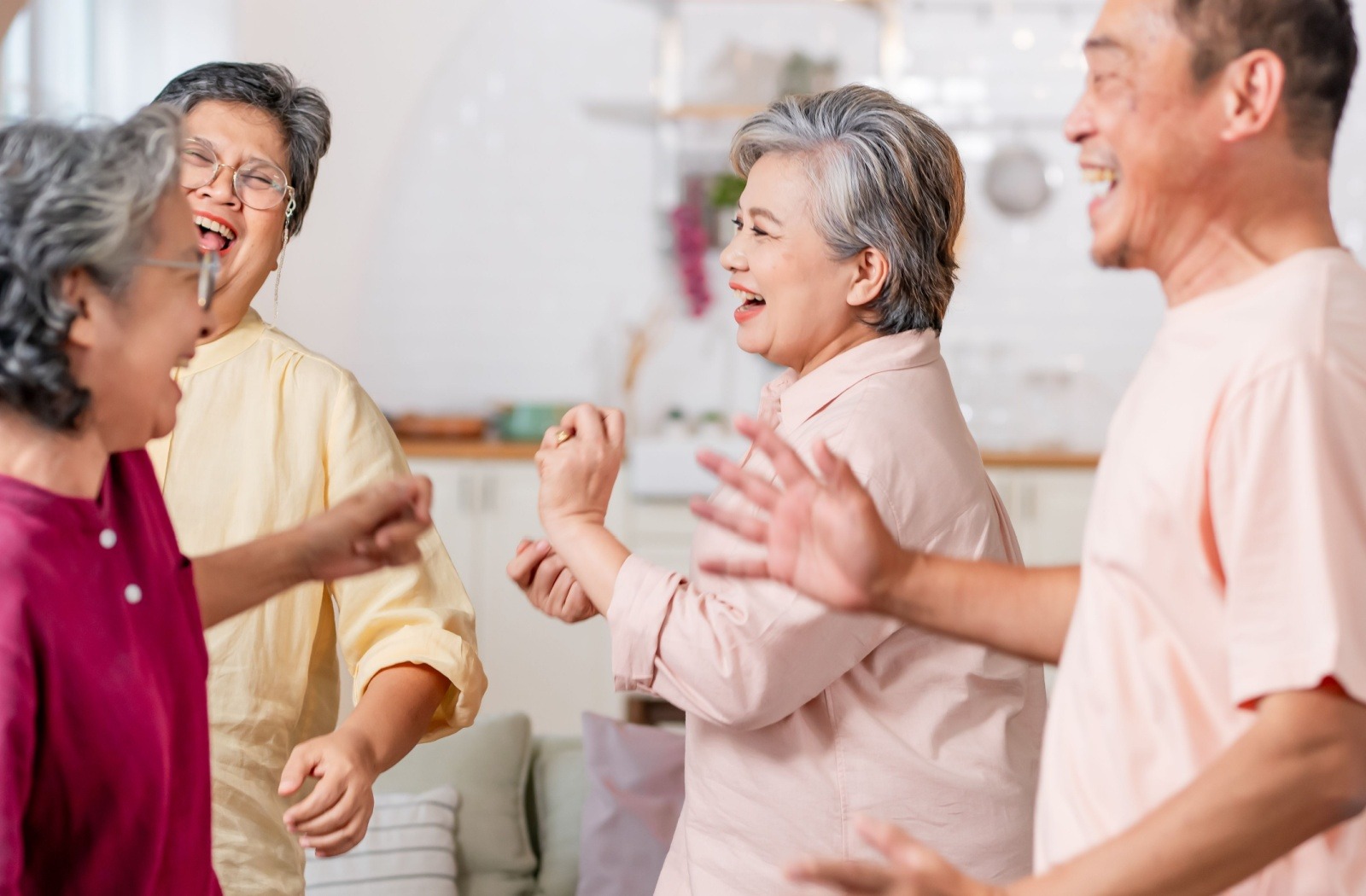 A group of 4 seniors laugh together as they line dance
