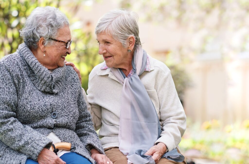 Two senior friends reminisce while sitting on a park bench.